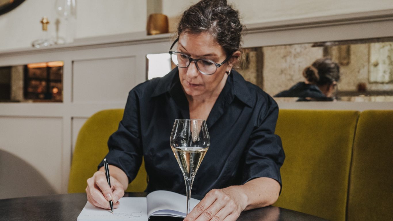 Nicole Wolbers writing tasting notes with a glass of sparkling wine